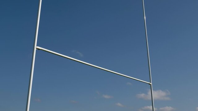 Low Angle Shot Looking Up at Rugby Posts as Rugby Ball Flies Over