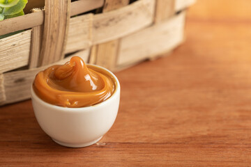 dulce de leche in a white container on a wooden table