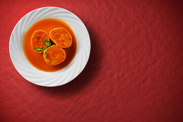 Three rondelles pasta on a white plate on a red background