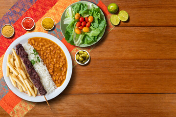 Lunch with meat skewer, beans, french fries and salad. Top view. Space for text.