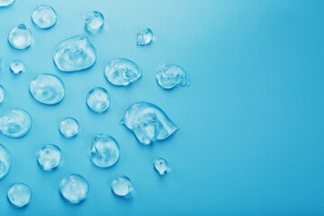 Drops of Gel with hyaluronic acid in the form of a smear of glossy texture on a blue background.