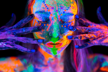 Beautiful young woman in neon light. Portrait of a model with fluorescent makeup posing in UV light...