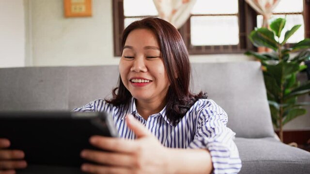 slow motion scene on adult asian woman using digital tablet with emotional surprise feeling after become a winner on online lottery monthly from website for lifestyle people concept