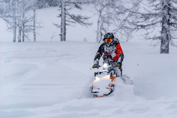 Fototapeta na wymiar Mountain snowmobile riders ride on the slopes