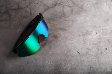 Sports glasses with a green mirrored lens and black frames on a black background