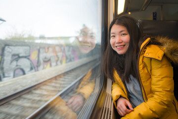 Fototapeta premium young beautiful and happy Asian Korean woman sitting on train looking out to window enjoying holidays travel in Europe smiling thoughtful and sweet