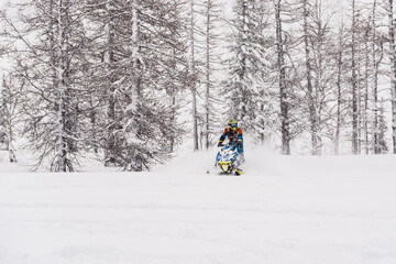 Mountain snowmobile riders ride on the slopes