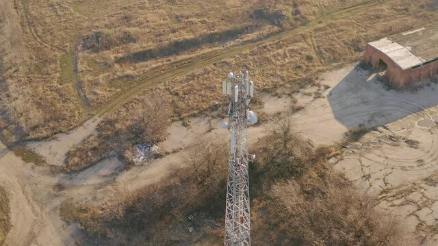 Mobile cell tower in the countryside - telecom station of cellular communication. Cellular tower 4G and 5G, providing work of mobile operators in rural area - aerial drone orbit shot.