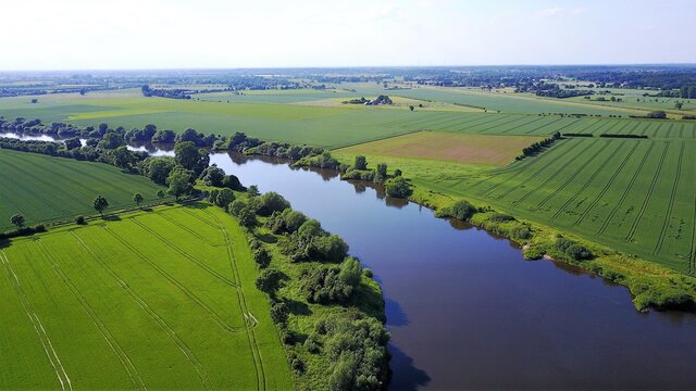 aerial view of a river and farmland with tractor lanes