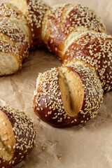 Fresh baked pretzel buns with sesame seeds closeup on paper