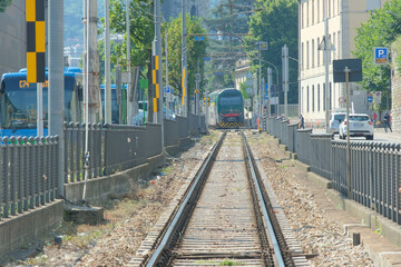 Obraz premium Un treno che viaggia sui binari in una città.