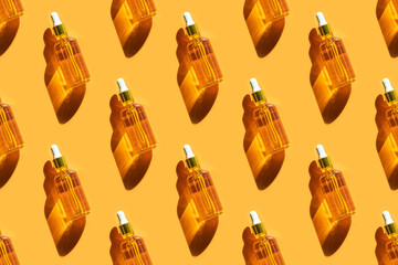 Seamless pattern of serum in glass bottle on orange background. Beauty, cosmetology, dermatology concept. Top view, flat lay.