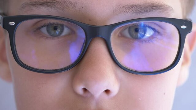 Teenage boy with blue light blocking glasses opening eyes and looking direct at camera. 4k video