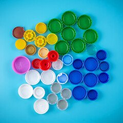 Colorful plastic bottle caps on a blue background, collecting plastic for recycling and reuse.