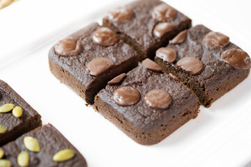flourless pumpkin chocolate brownies set on white cafe table.