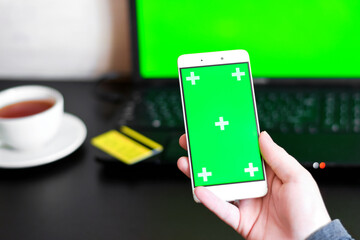 Close Up of a Smartphone with Green Screen for chroma key compositing. Person is shopping online with credit card and phone on internet. Concepts of Internet commerce, online banking to pay