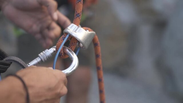 Climber preparing for climbing up the mountain by checking his rope. Climbing extreme active sport. Active people, outdoor activities. Rope and hooks preparation detail shot. close up