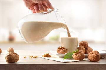 Man filling a glass with walnut drink from a jug