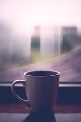 Steaming coffee cup on a rainy day window background