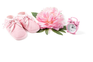 Pink baby girl shoes with peony flower and alarm clock on a white background. Newborn greeting card or invitation. Copy space.