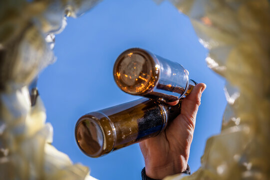 Flaschen &uuml;ber einem M&uuml;lleimer als Symbol f&uuml;r M&uuml;llentsorgung oder Flaschensammeln wegen Armut