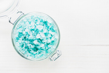 Blue aroma bath salt in a glass jar on white wooden background. Spa, skincare concept.