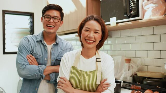 slow motion scene on asian lover man and  woman arm crossed together and smile and laugh with happiness inside kitchen room to begin cooking food for people lifestyle concept