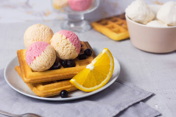 Traditional Belgian waffles with fruit ice-cream on gray plate. Orange and blueberry taste