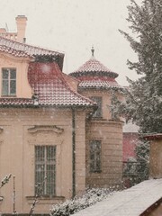 Obraz premium old house in the snow during spring season after unexpected snowstorm near prague castle
