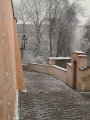 snow covered old historic stairs with walls leading to the prague castle during unexpected spring snowstorm blizzard