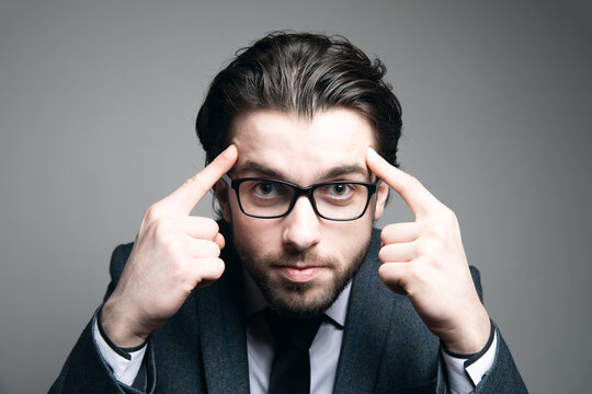 a man in a suit and glasses put his fingers on his temples