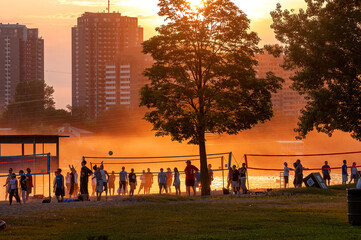Crowd of people playing volleyball through a hot and hazy sunset