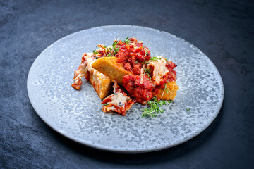 Modern style traditional Italian polenta alla sarda con salsiccia with meat sausage served as close-up on a Nordic design plate with copy space