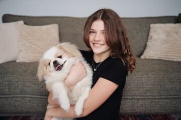 Young dog owner girl plays with her dog at home indoors