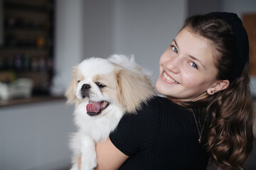 Young dog owner girl plays with her dog at home indoors