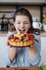 Adorable girl holding a Very berry cake. Tart with berries. Emotions concept