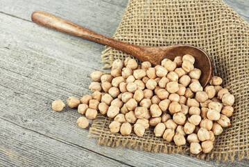 Dried chickpeas in wooden spoon on wooden table. Heap of legume chickpea. Healthy and natural...