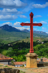 Fototapeta na wymiar The cross in front of the Igreja Matriz de Santo Antonio church and the hilly and green environs of Tiradentes, Minas Gerais, Brazil