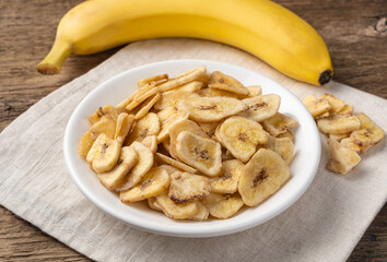 Sweet dry bananas with a white plate on a background of fresh banana.