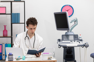 A young primary care physician reviews book calendar entries about his patients. The doctor's office