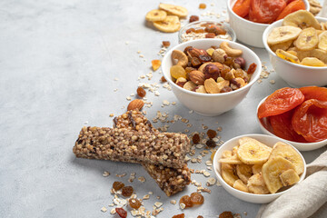 Granola bar, nuts and dried fruits on a gray background with space to copy.