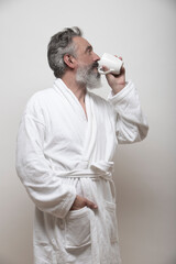 older man with beard drinking coffee in bathrobe