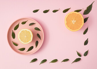 Fresh lemon and orange on a pastel pink tray surrounded by leaves on a pink background. Top view. Flat lay. Copy space for text. Minimal aesthetic.