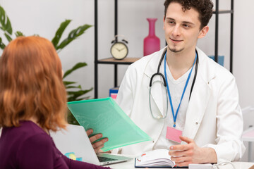 A doctor talks to a redheaded patient with a smile on his face. An adult woman in a doctor's office