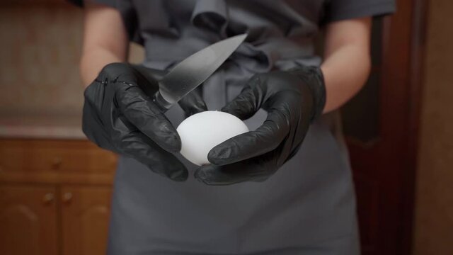 A girl pastry chef smashes an egg with a knife, a close-up, a slow-motion