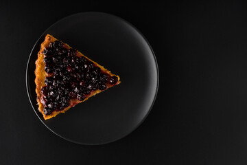 Piece of pie with carrots and currants sprinkled on top on black background f isolation
