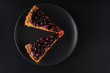 Two slices of Pie with carrots and currants sprinkled on top on a black background isolated