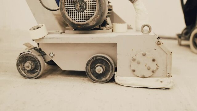 Workers grind the concrete floor at the construction site. Prepares the floor for polyurethane mortar