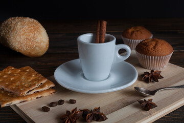 Hot coffee with anise, cinnamon and muffins on an old table. 