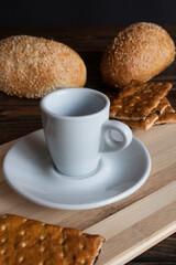 A cup of aromatic black coffee and coffee beans on a wooden table with cinnamon sticks and a French croissant. Coffee break. A cup of coffee. 